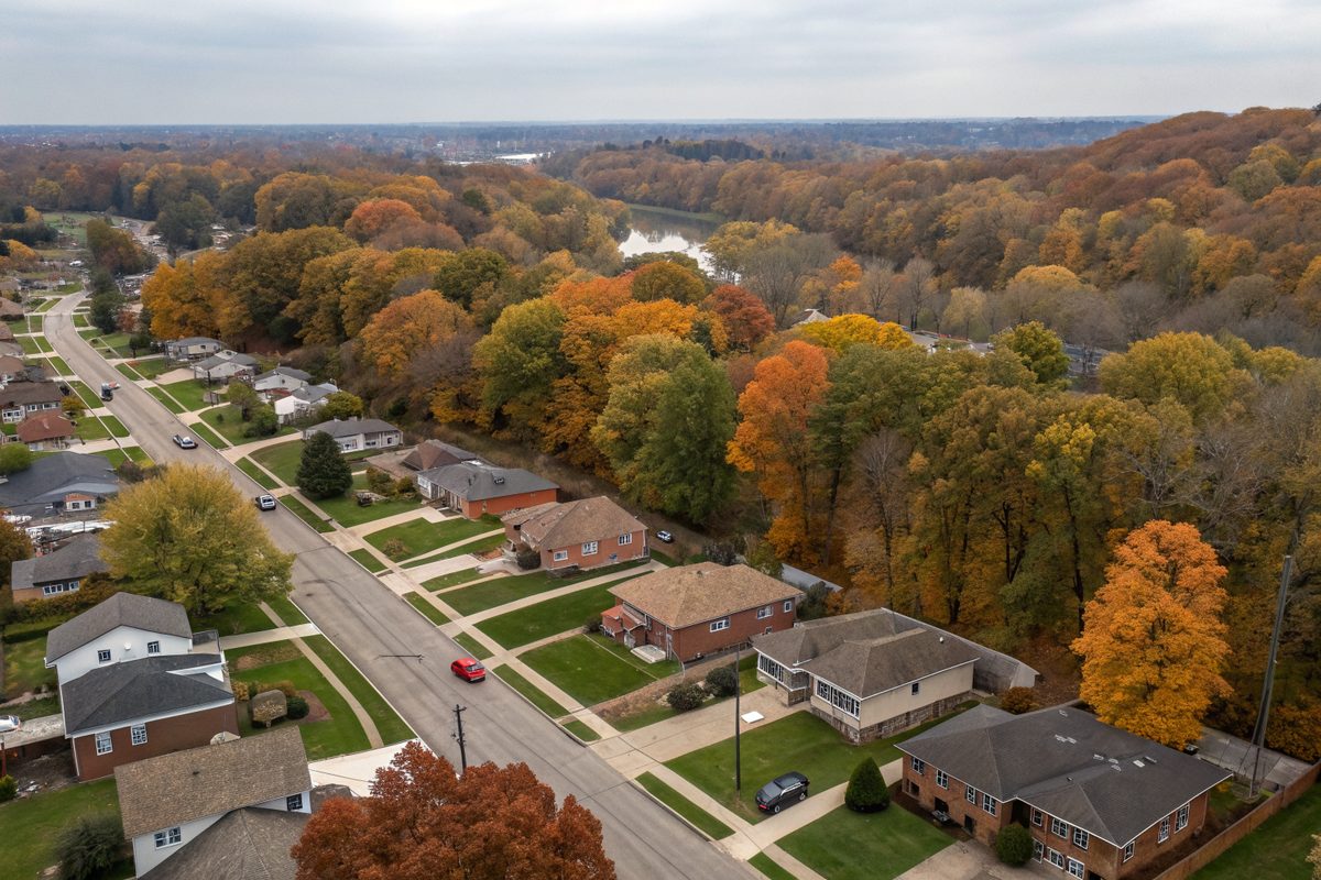 Aerial view of an older suburb of brick and frame houses with autumn trees and a creek valley